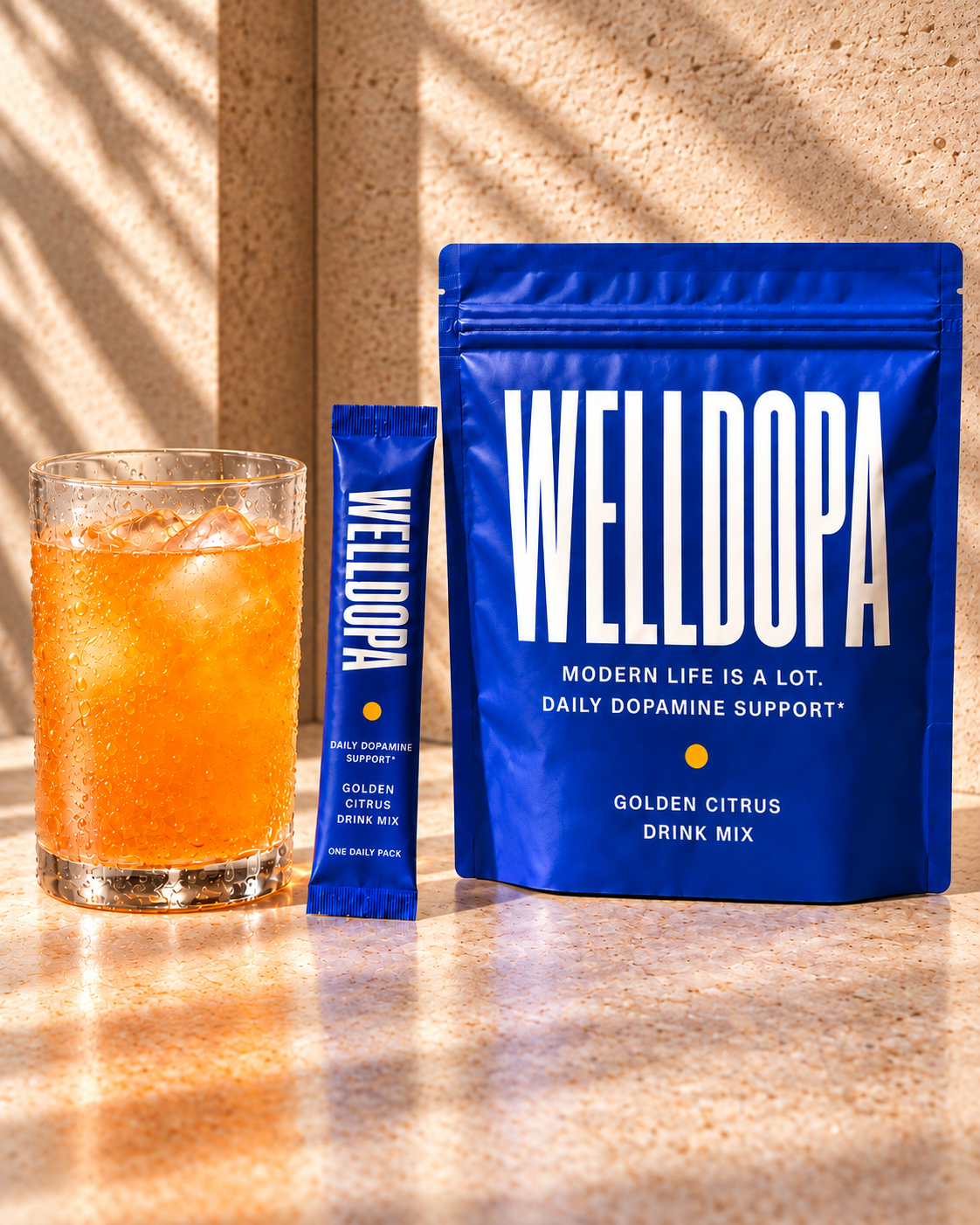 Local concept image: orange Golden Citrus drink beside a cobalt WellDopa pouch and stick, both carrying working dopamine-support copy